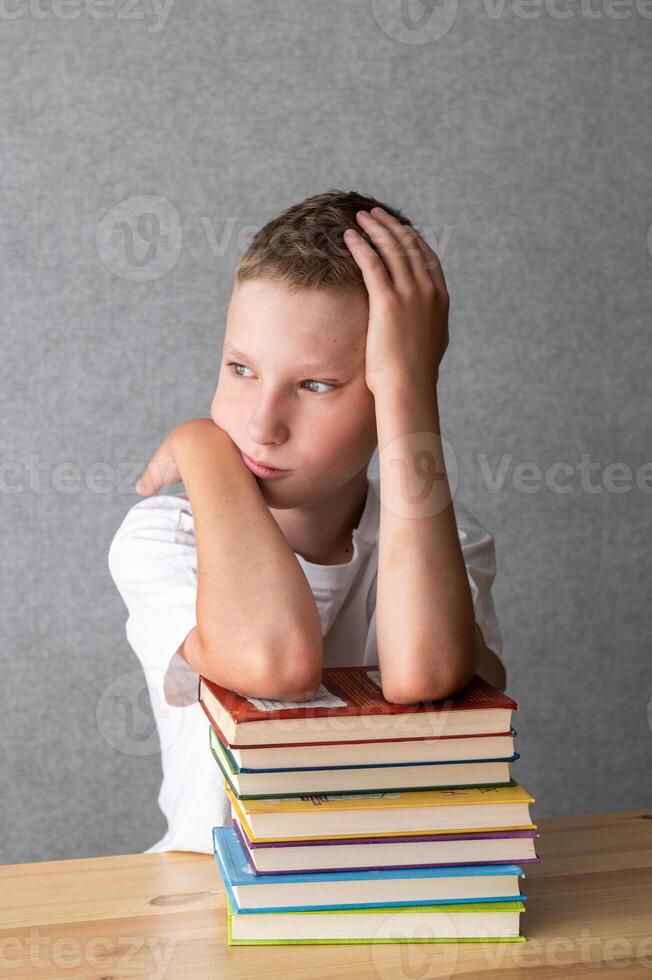 Pensive Young Boy Resting on a Stack of Books. World Dyslexia Awareness Day photo