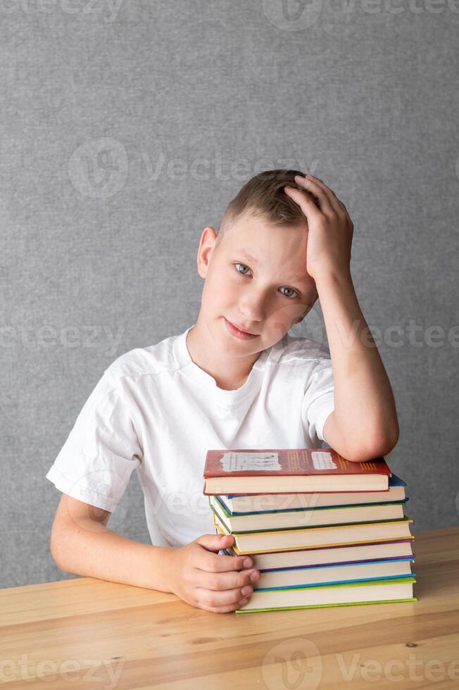 Pensive Young Boy Resting on a Stack of Books. World Dyslexia Awareness Day photo