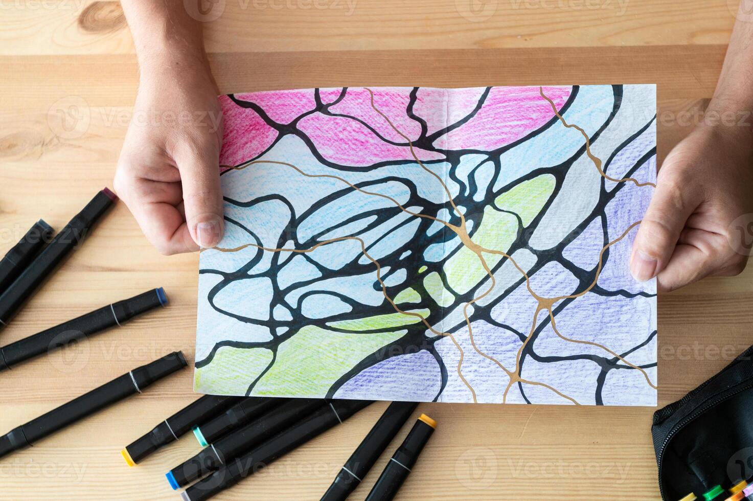 Person Coloring Artwork with Markers on Wooden Table photo
