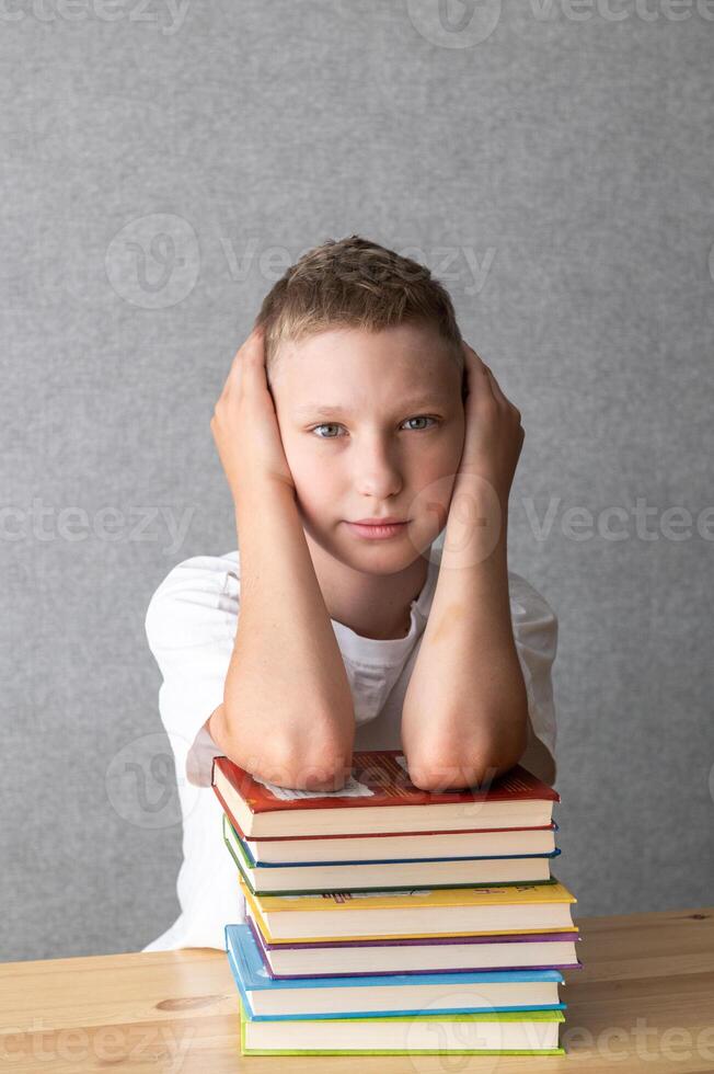 Young Boy Resting Head on Stack of Books. World Dyslexia Awareness Day photo