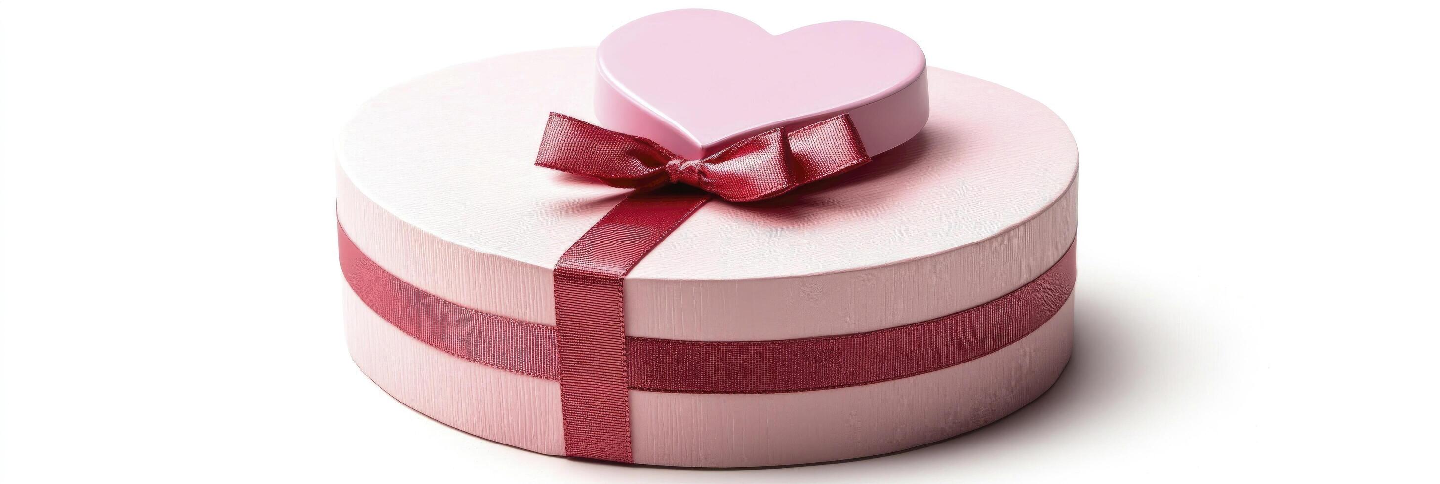 A red ribbon bow on the bottom of a pink gift box with a heart-shaped box on top photo
