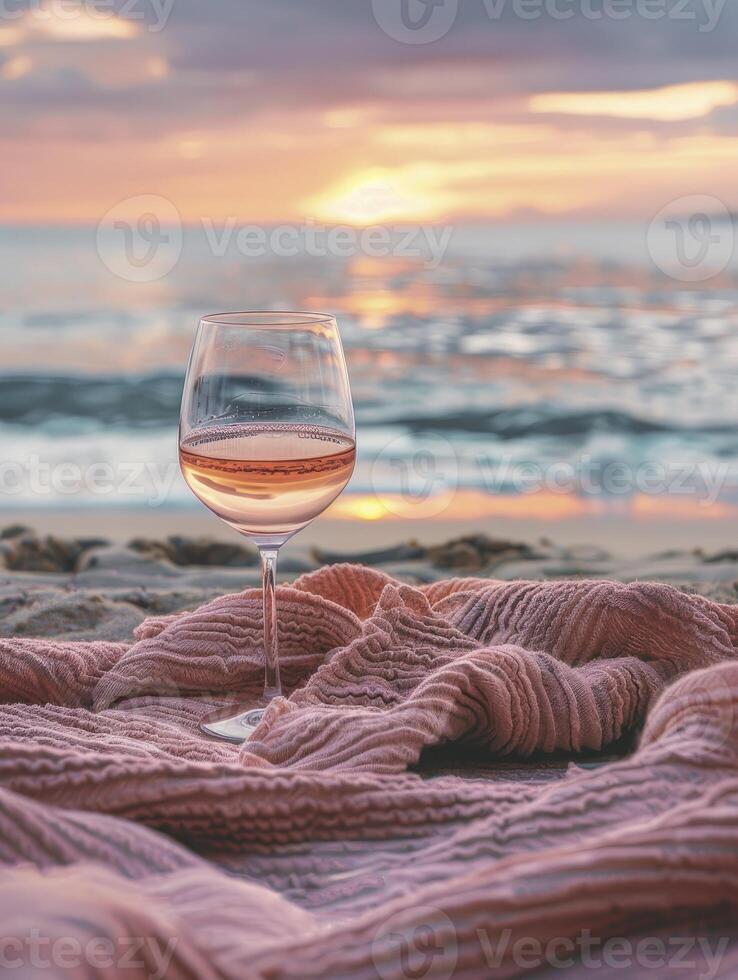 A glass of rose wine on pink blanket at sea beach with sunshine in background photo