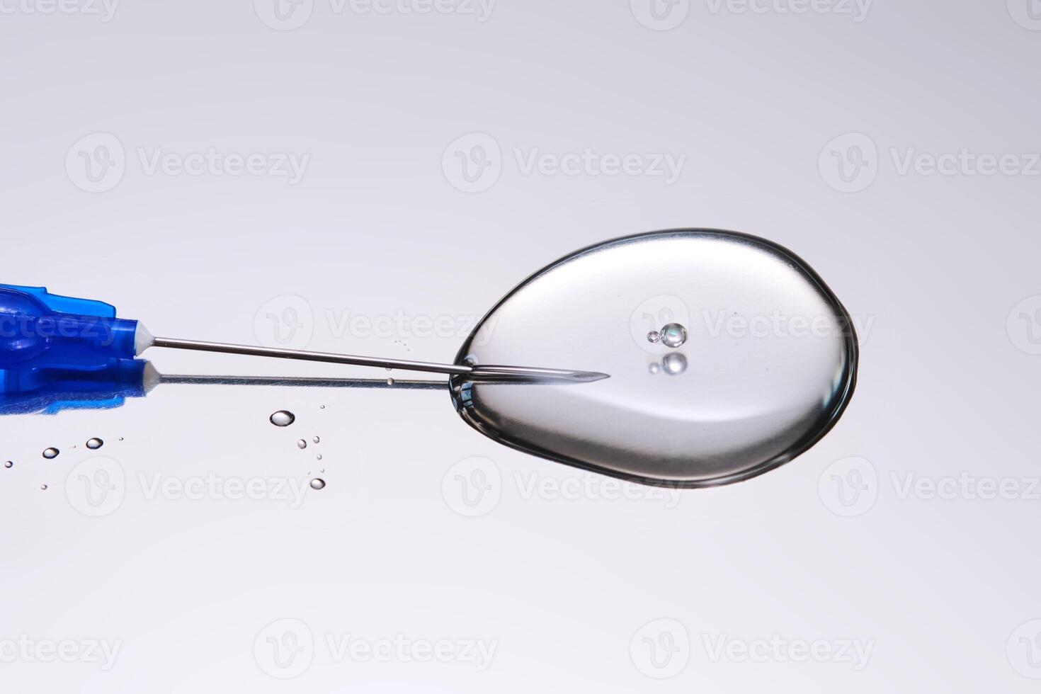 A drop of medicine flowing from a syringe with a needle. photo