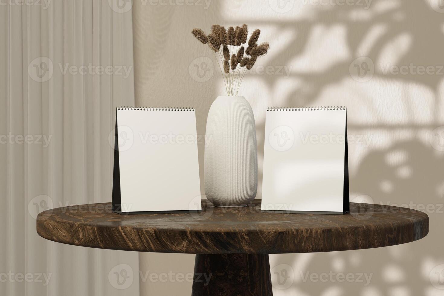 Two blank calendar sitting on a table in front of a vase of dried reeds photo