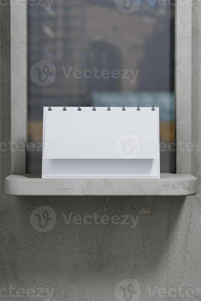 A white desk calendar sitting on a ledge with a window behind it photo