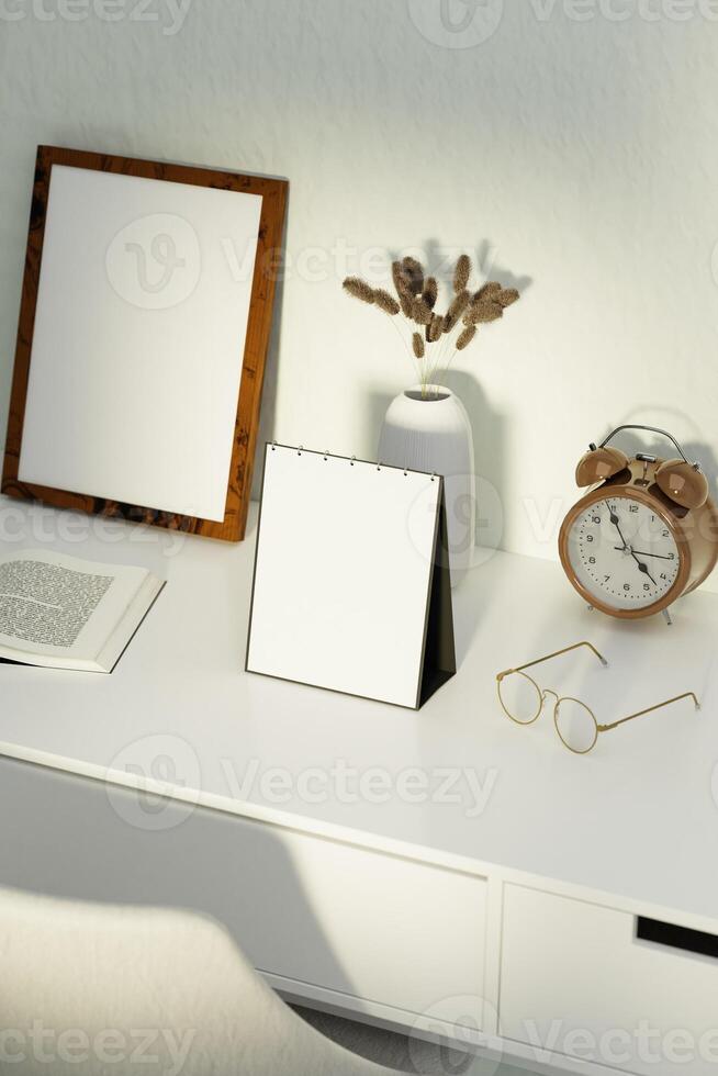 A blank desk calendar on a desk with glasses, alarm clock and a picture frame photo