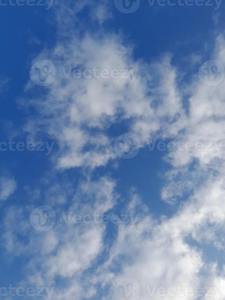 White clouds in the blue sky. Beautiful bright blue background. Light cloudy, good weather. Curly clouds on a sunny day. photo