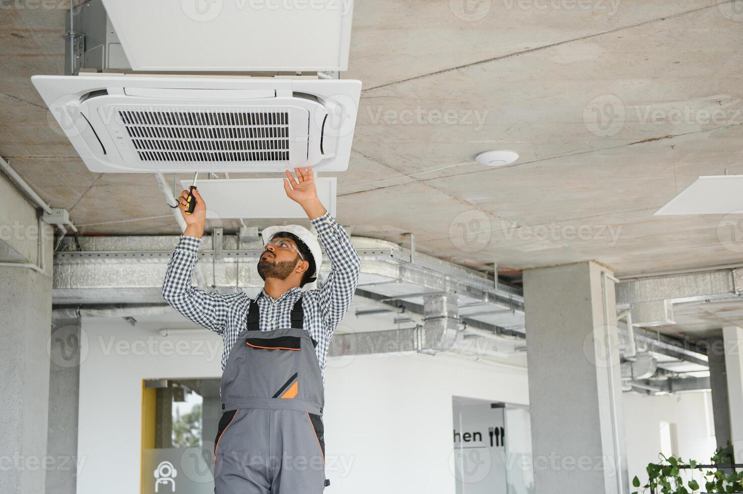 Professional technician maintaining modern air conditioner indoors. Space for text photo