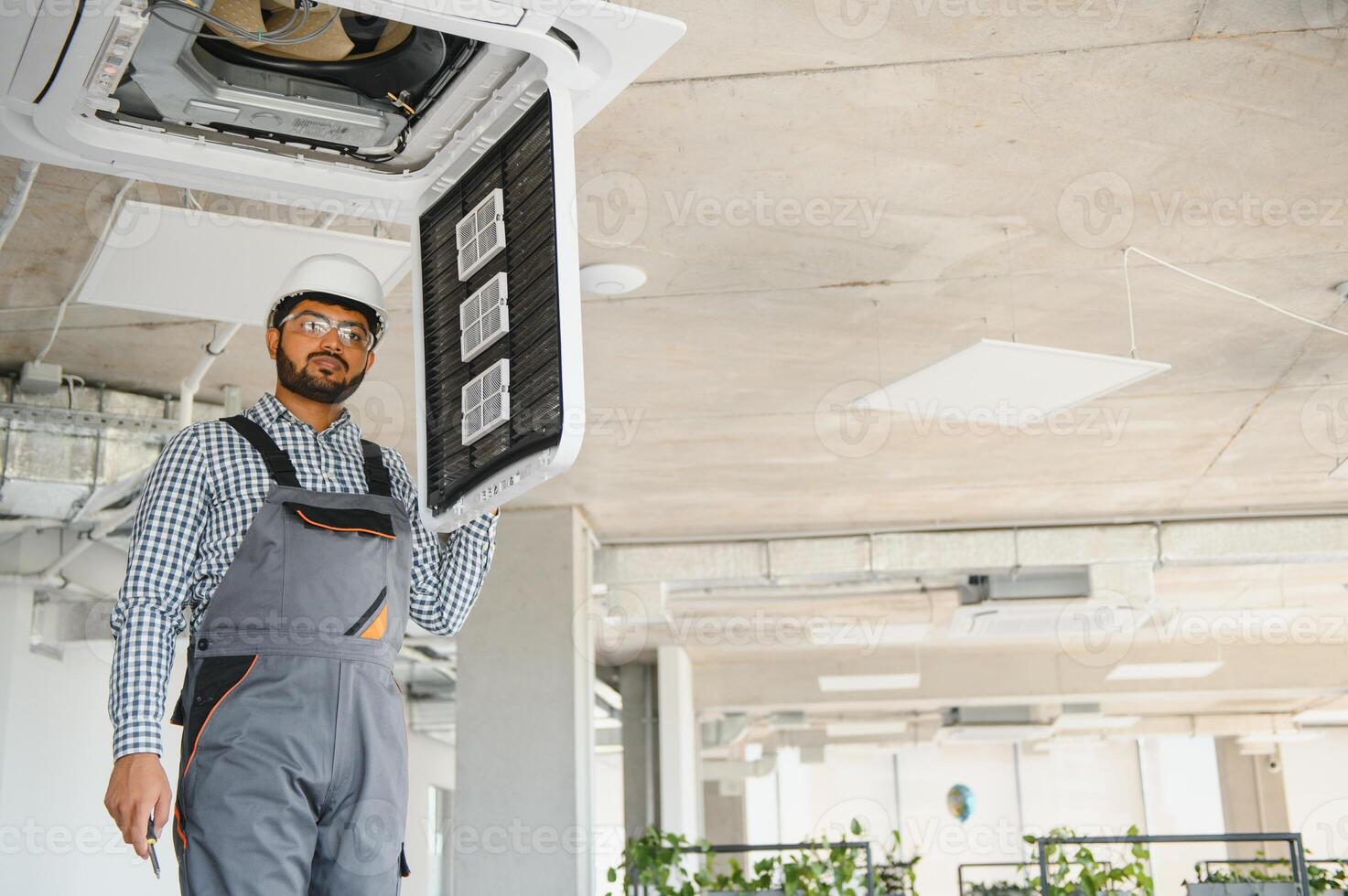 Professional technician maintaining modern air conditioner indoors. Space for text photo