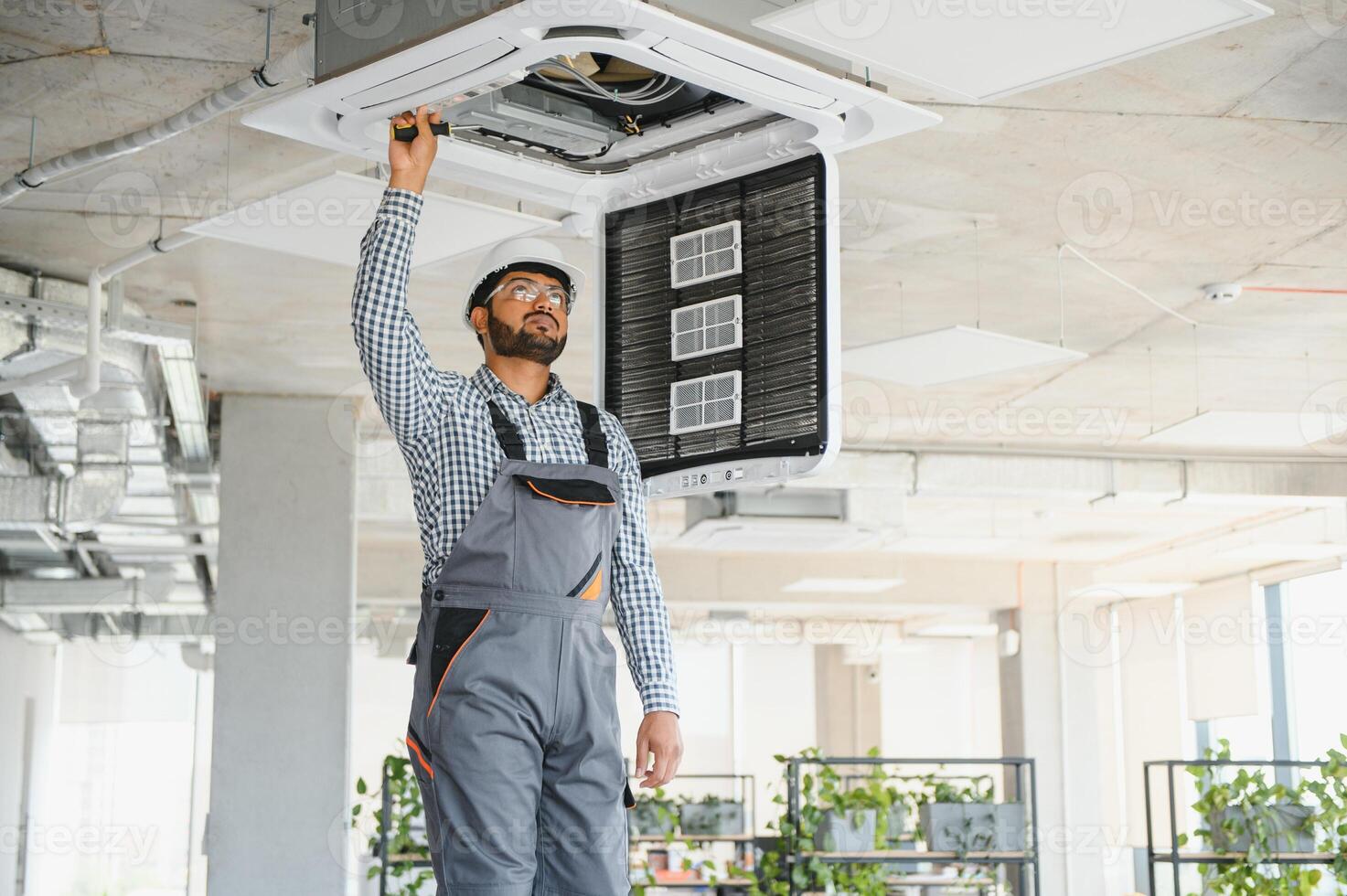 Professional technician maintaining modern air conditioner indoors. Space for text photo