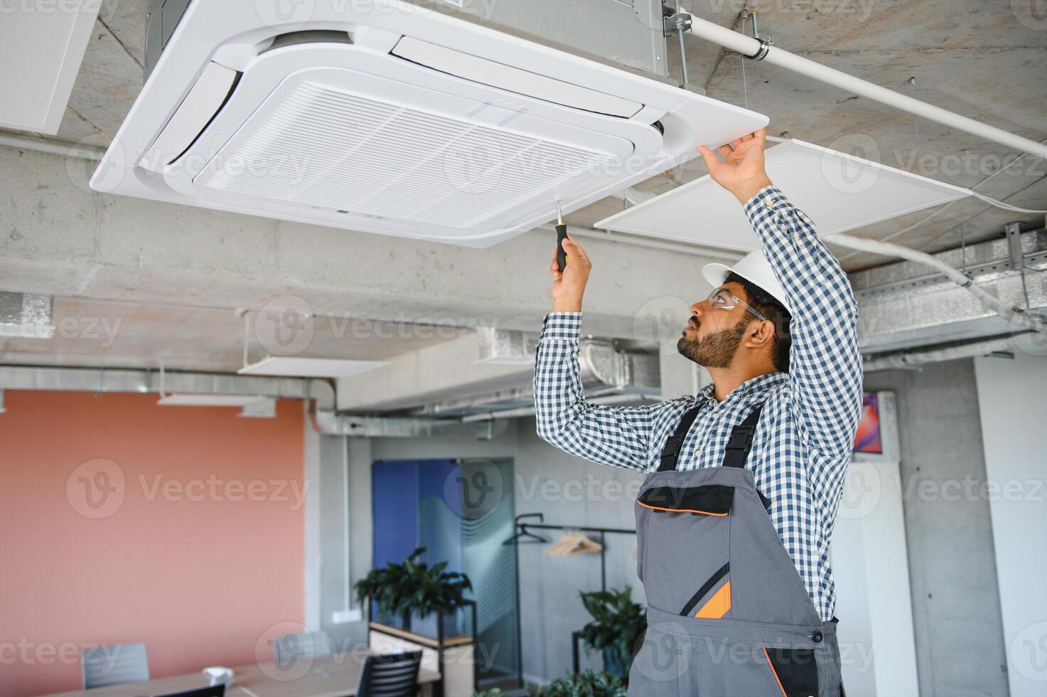 Professional technician maintaining modern air conditioner indoors. Space for text photo