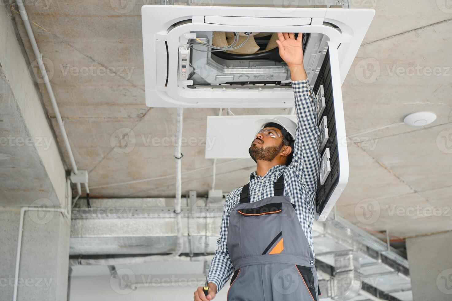 Professional technician maintaining modern air conditioner indoors. Space for text photo