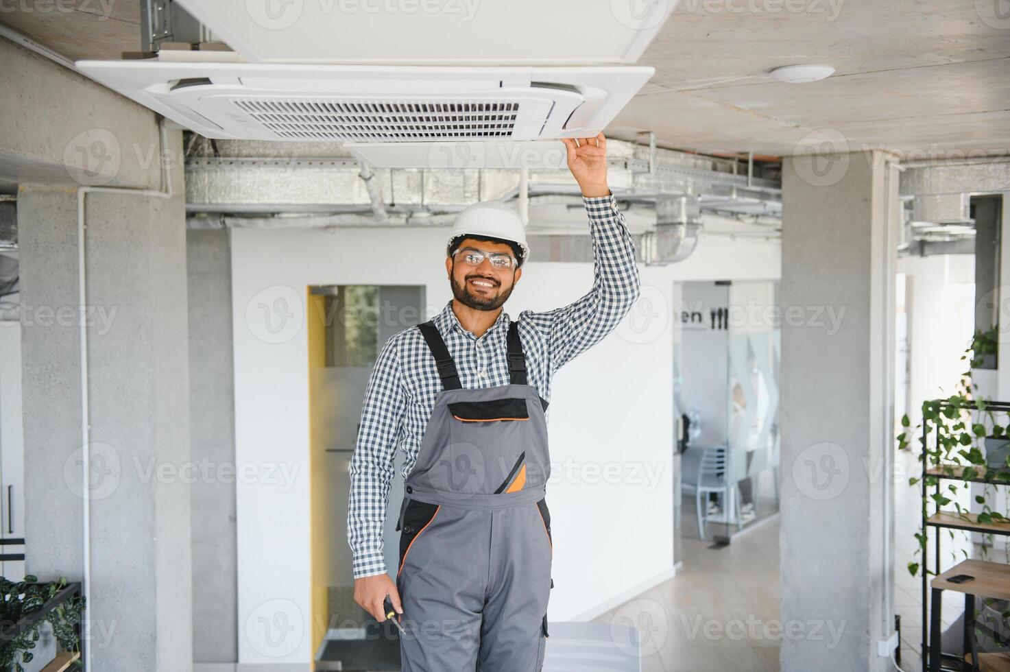 Professional technician maintaining modern air conditioner indoors. Space for text photo