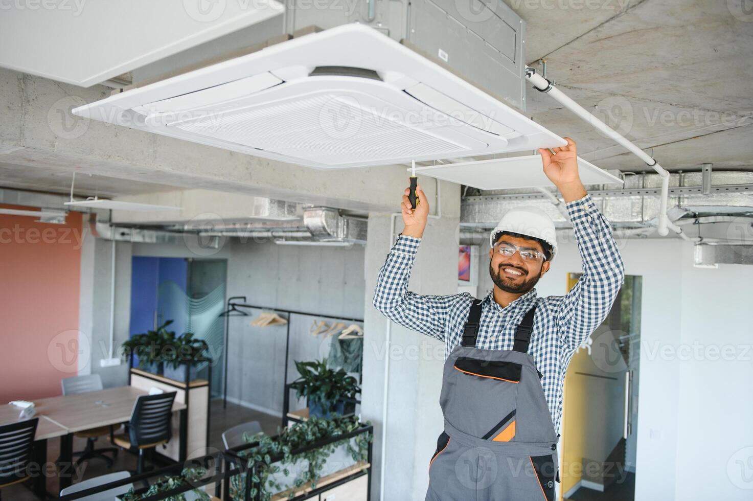 Professional technician maintaining modern air conditioner indoors. Space for text photo