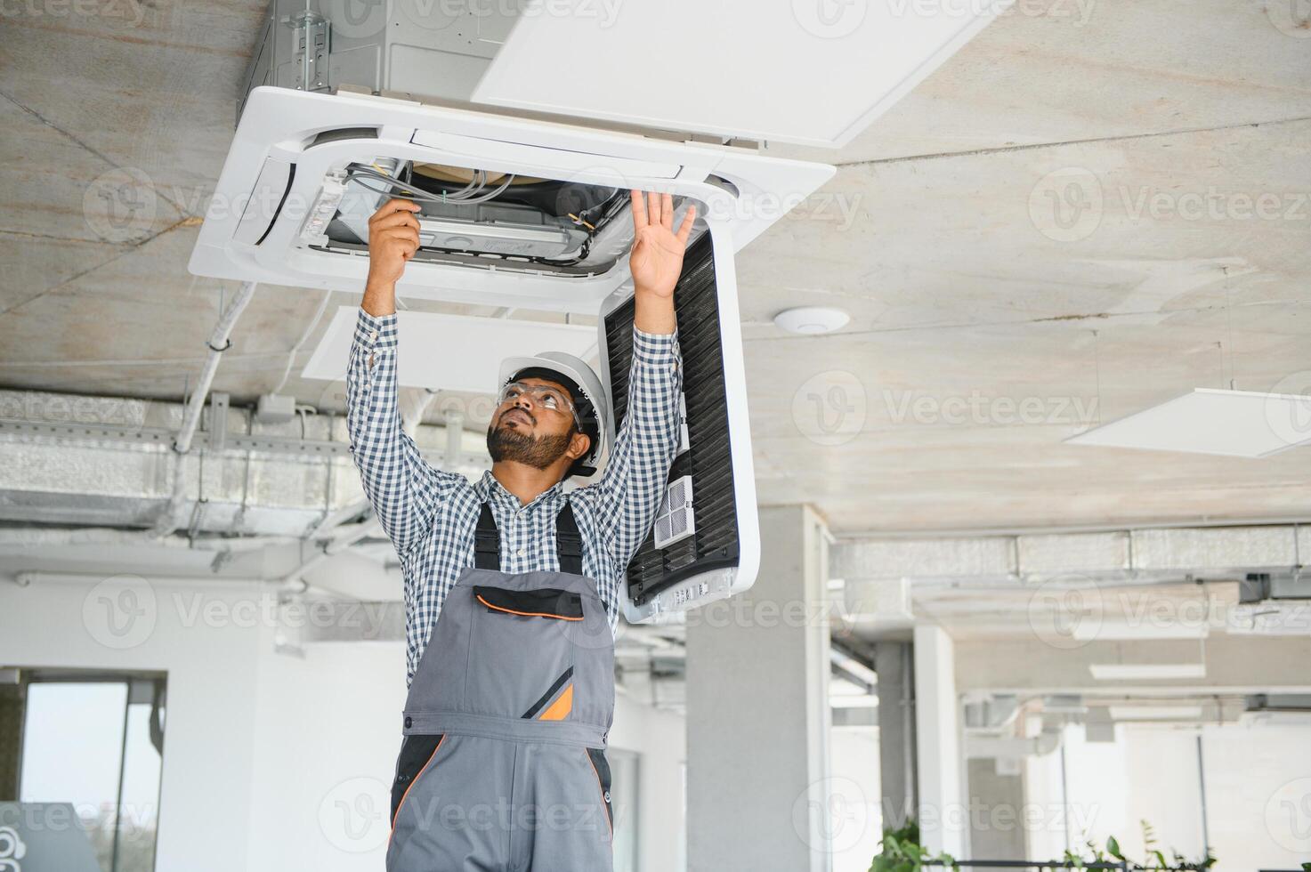 Professional technician maintaining modern air conditioner indoors. Space for text photo