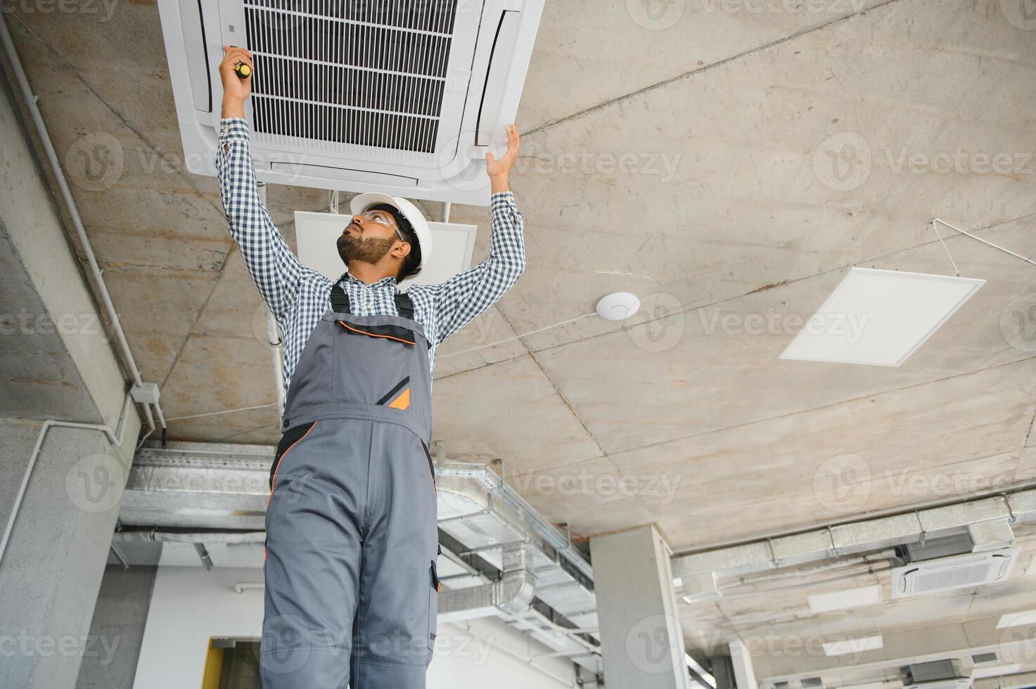 Professional technician maintaining modern air conditioner indoors. Space for text photo