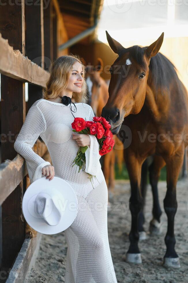 Beautiful model girl stands in a long dress with a horse photo