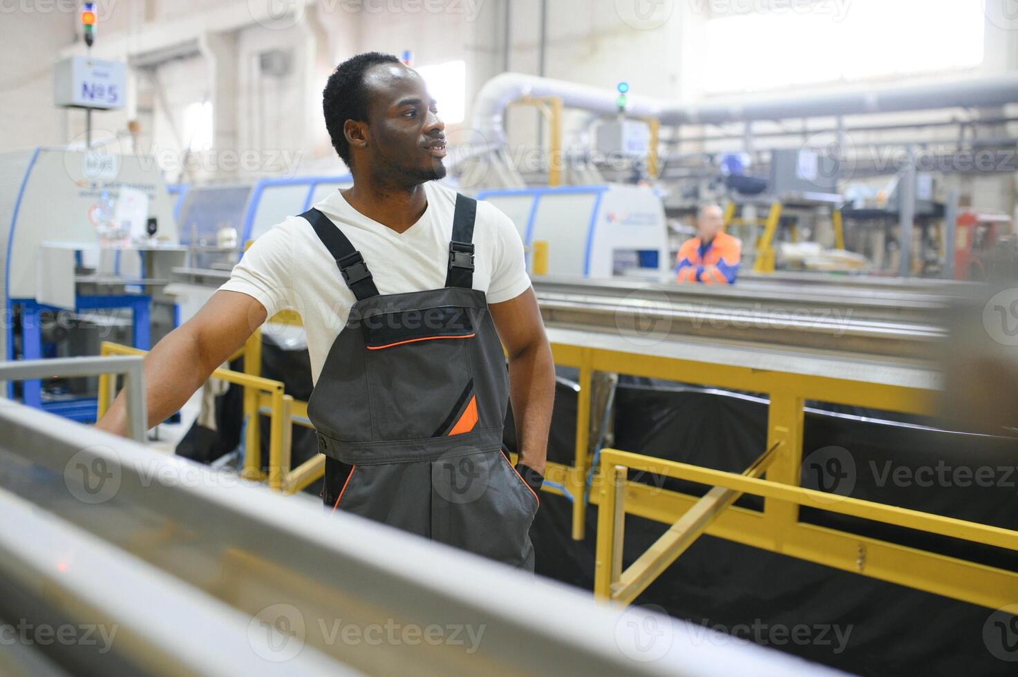 Portrait of African American male engineer in uniform and standing in industrial factory photo