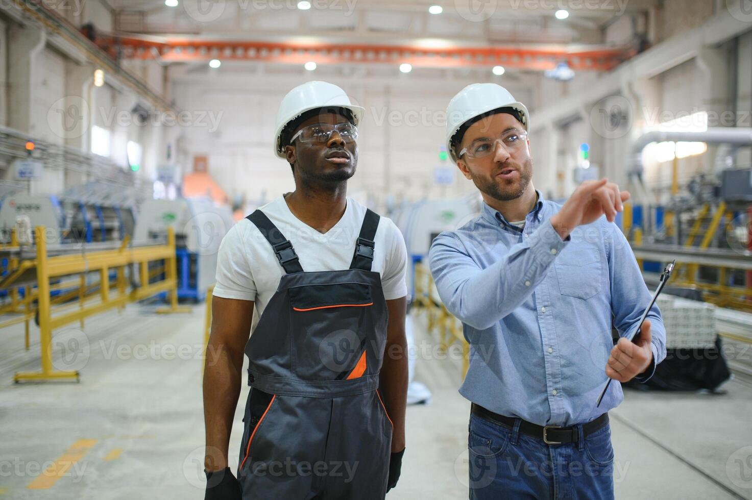 Two workers in production plant as team discussing, industrial scene in background photo