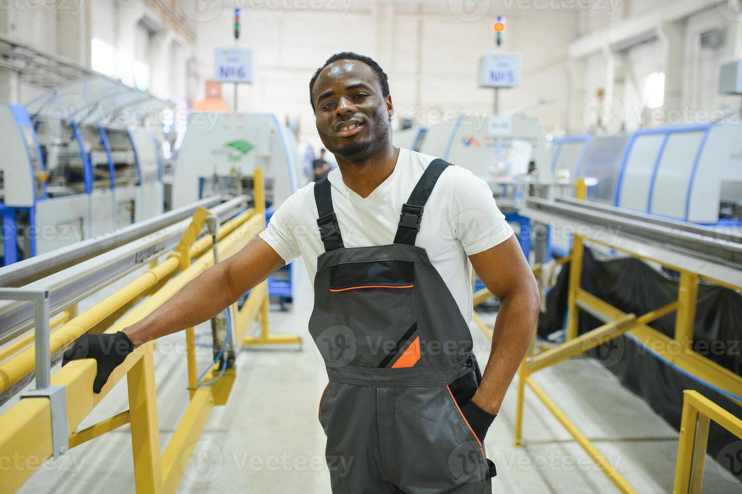 Portrait of African American male engineer in uniform and standing in industrial factory photo