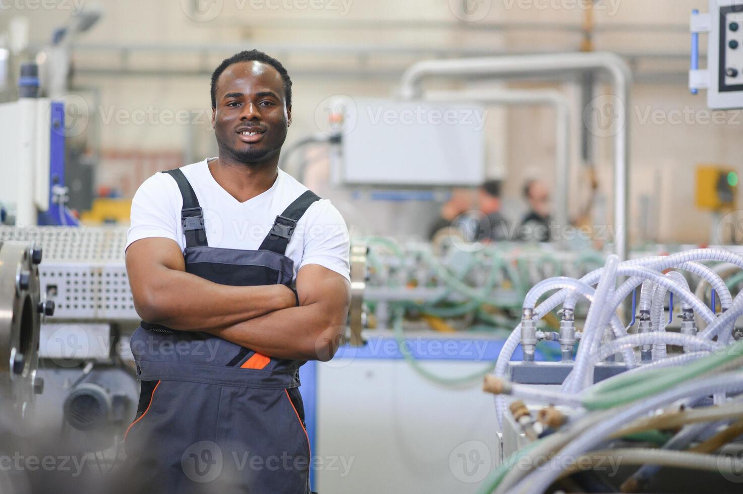 Portrait of African American male engineer in uniform and standing in industrial factory photo