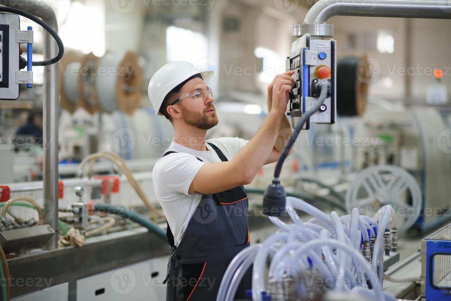 Smiling and happy employee. Industrial worker indoors in factory. Young technician with hard hat photo