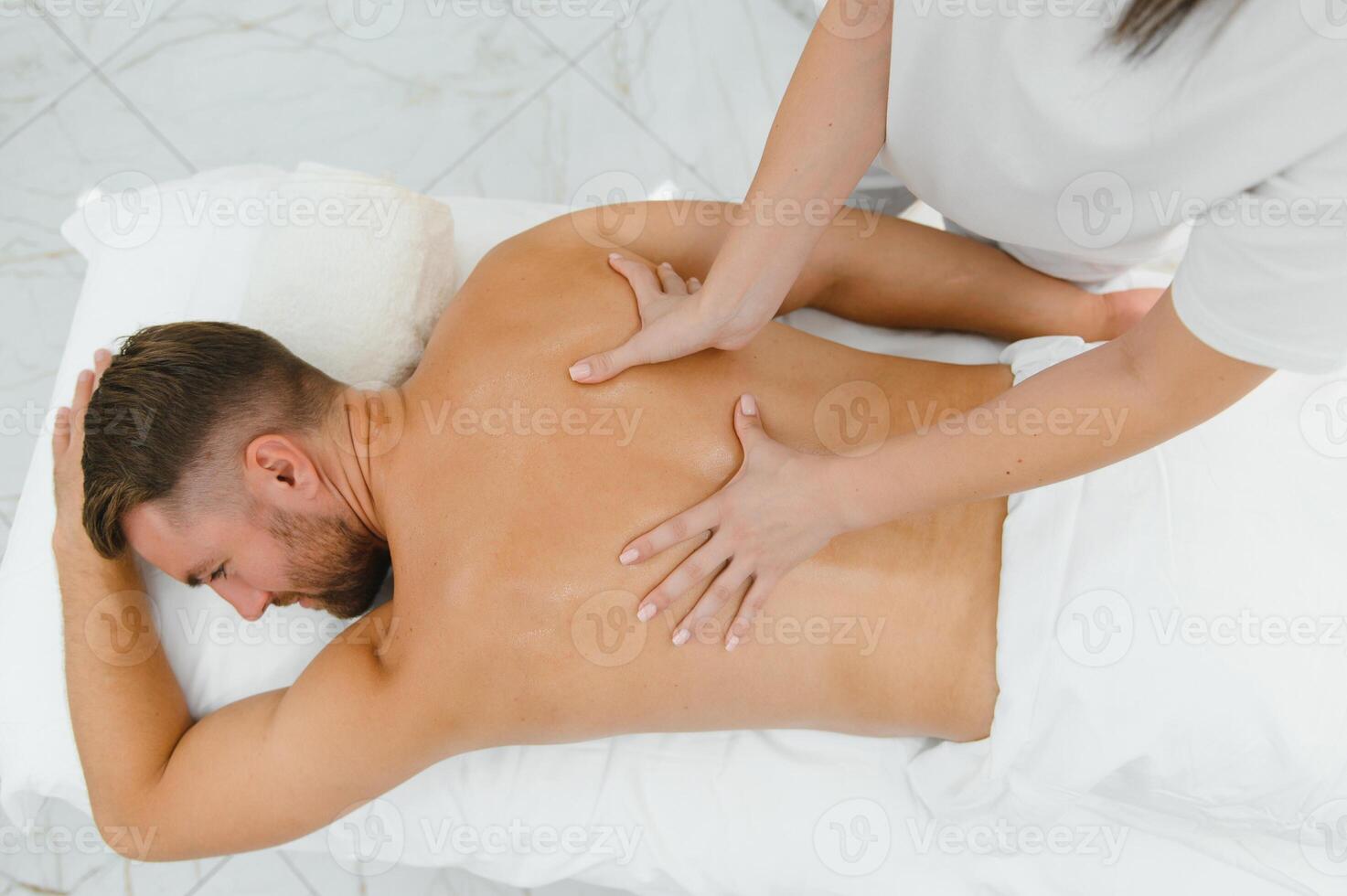Young man having a massage by a professional masseuse photo