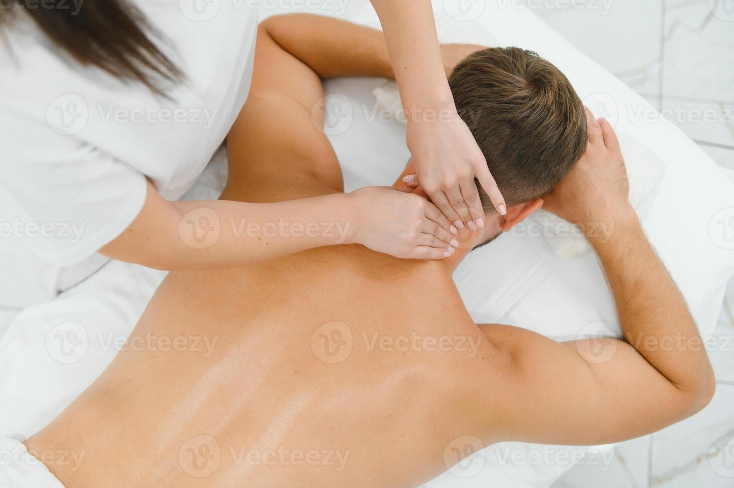 Young man having a massage by a professional masseuse photo