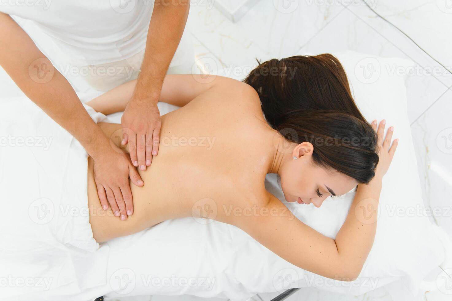 Osteopath massaging back of woman lying on front in health spa photo