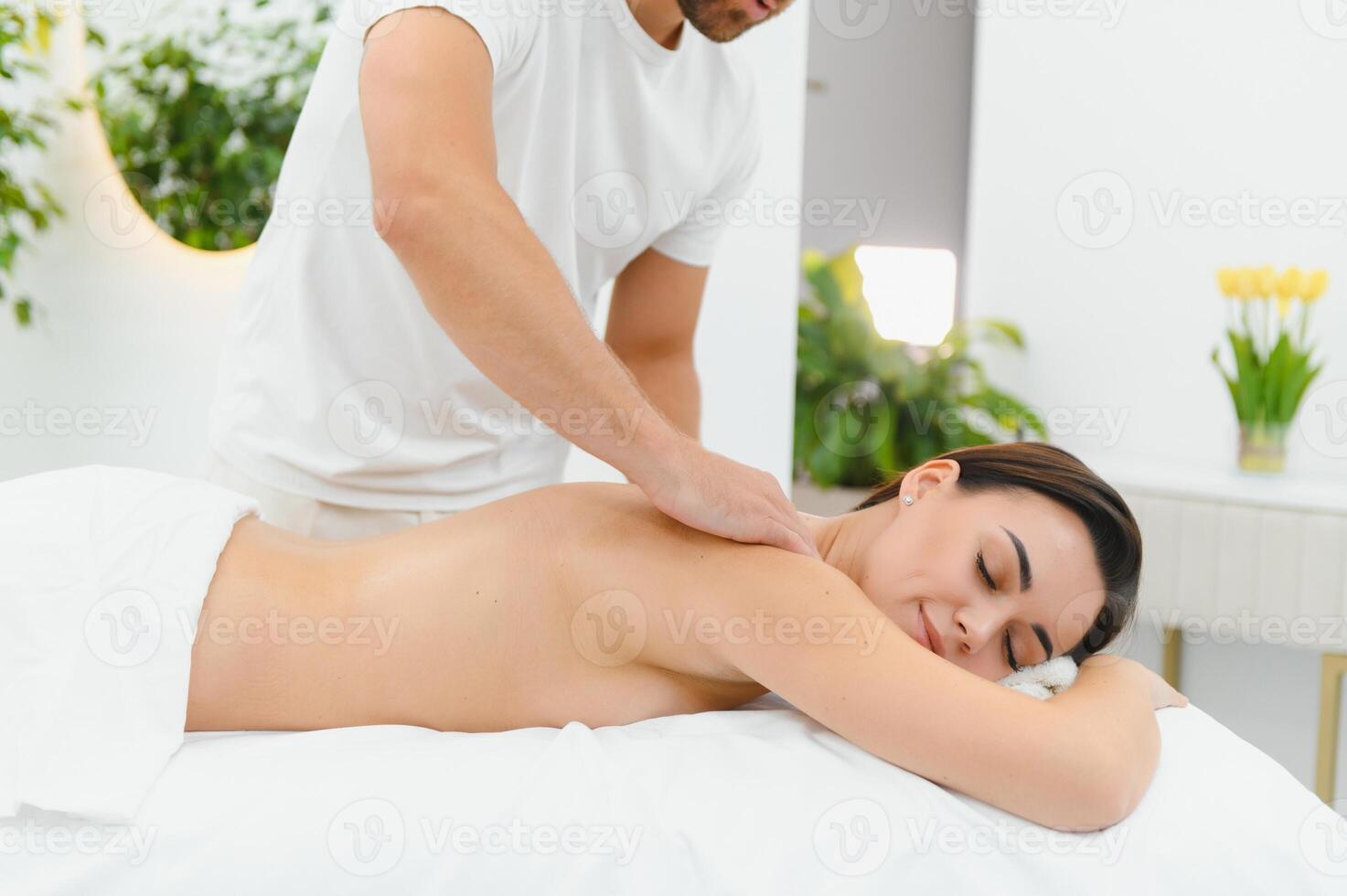 Osteopath massaging back of woman lying on front in health spa photo
