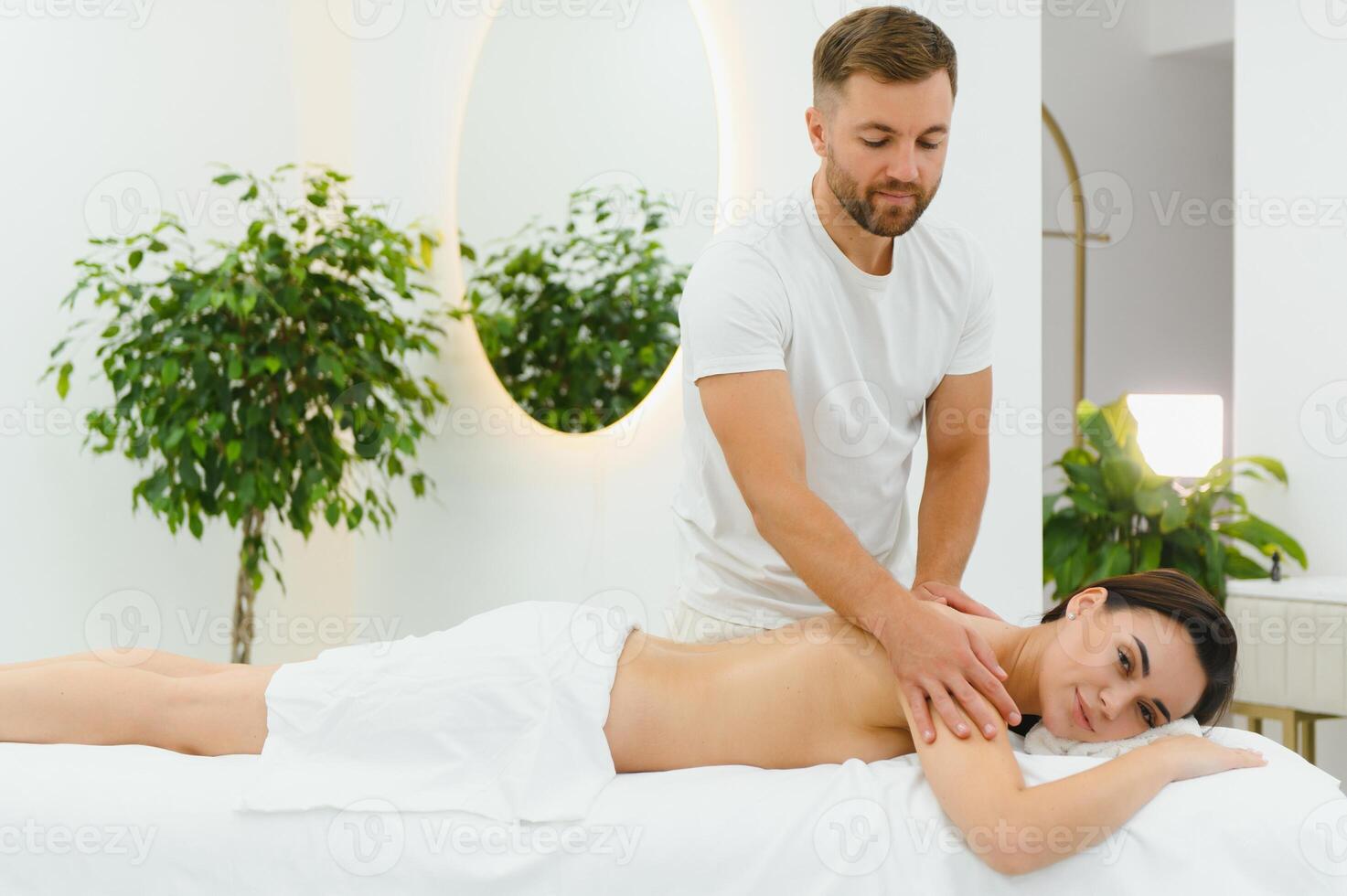 Osteopath massaging back of woman lying on front in health spa photo