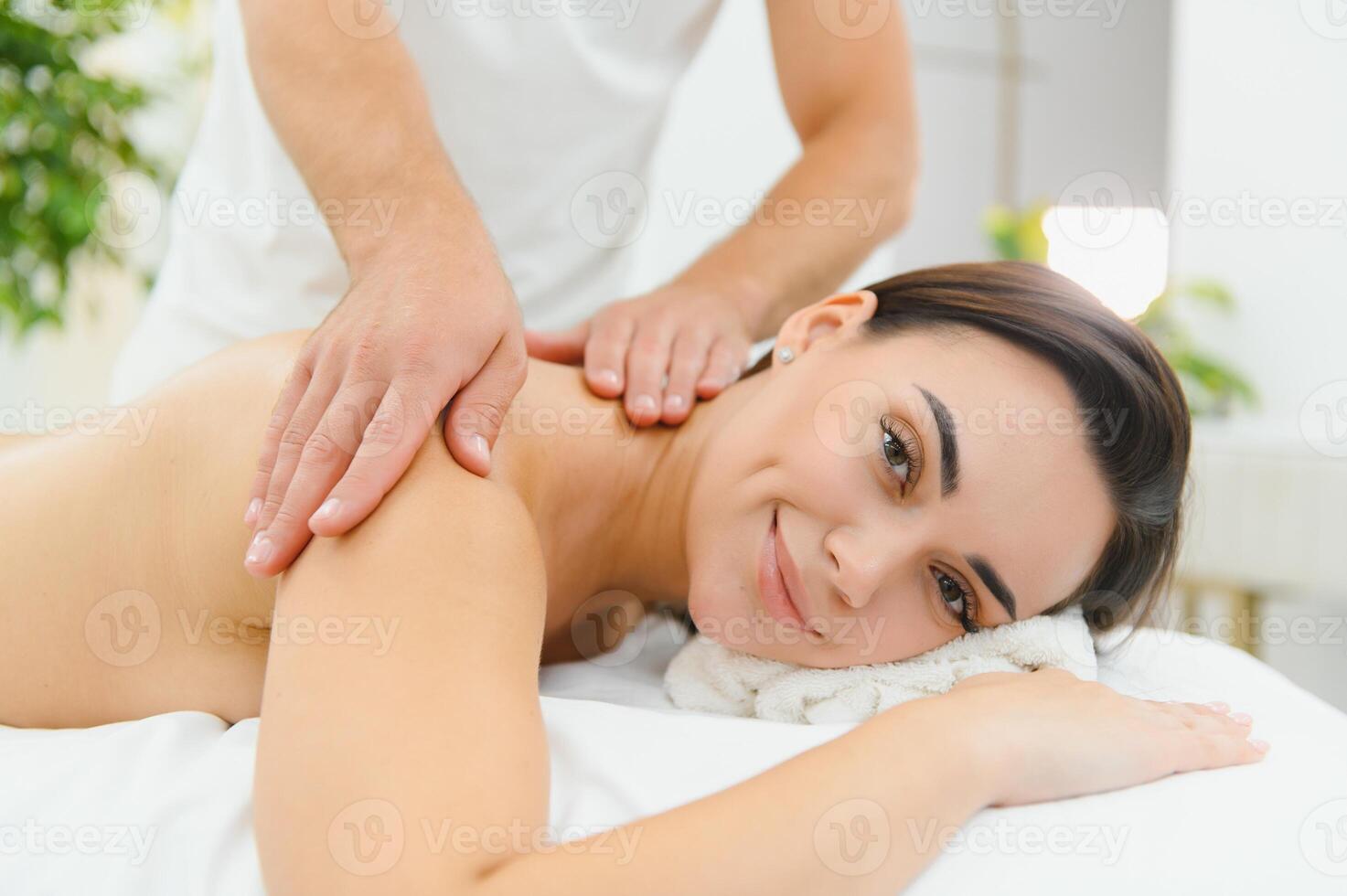 Osteopath massaging back of woman lying on front in health spa photo
