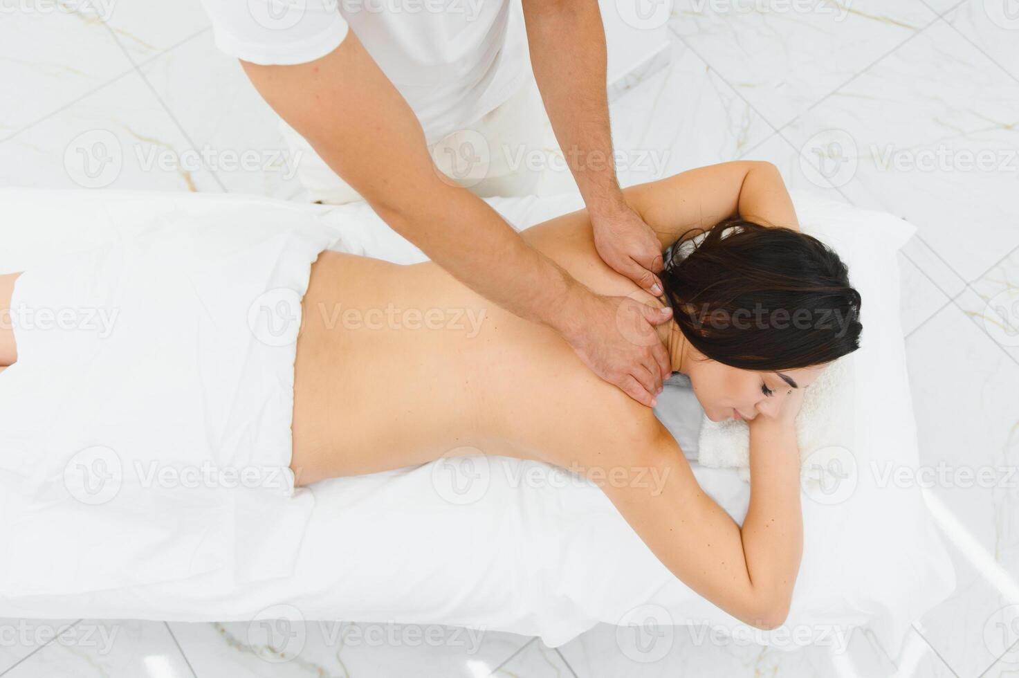 Osteopath massaging back of woman lying on front in health spa photo