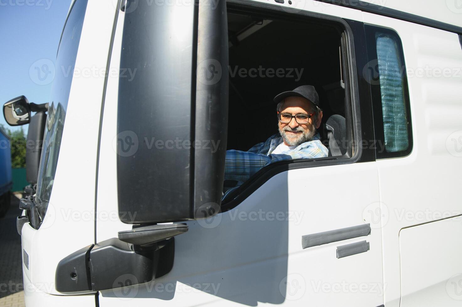Looking through the door window, sitting inside. Truck driver in casual clothes photo