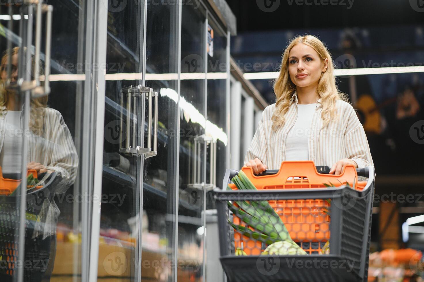 Young cool customer woman wear casual clothes shopping at supermaket store grocery shop buying with trolley cart choose products inside hypermarket photo