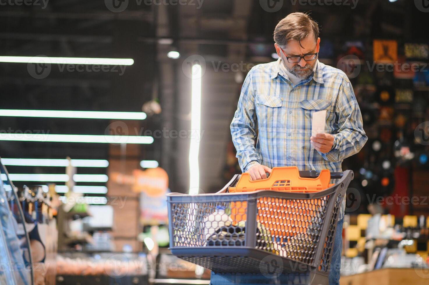 Minded man viewing receipts in supermarket and tracking prices photo