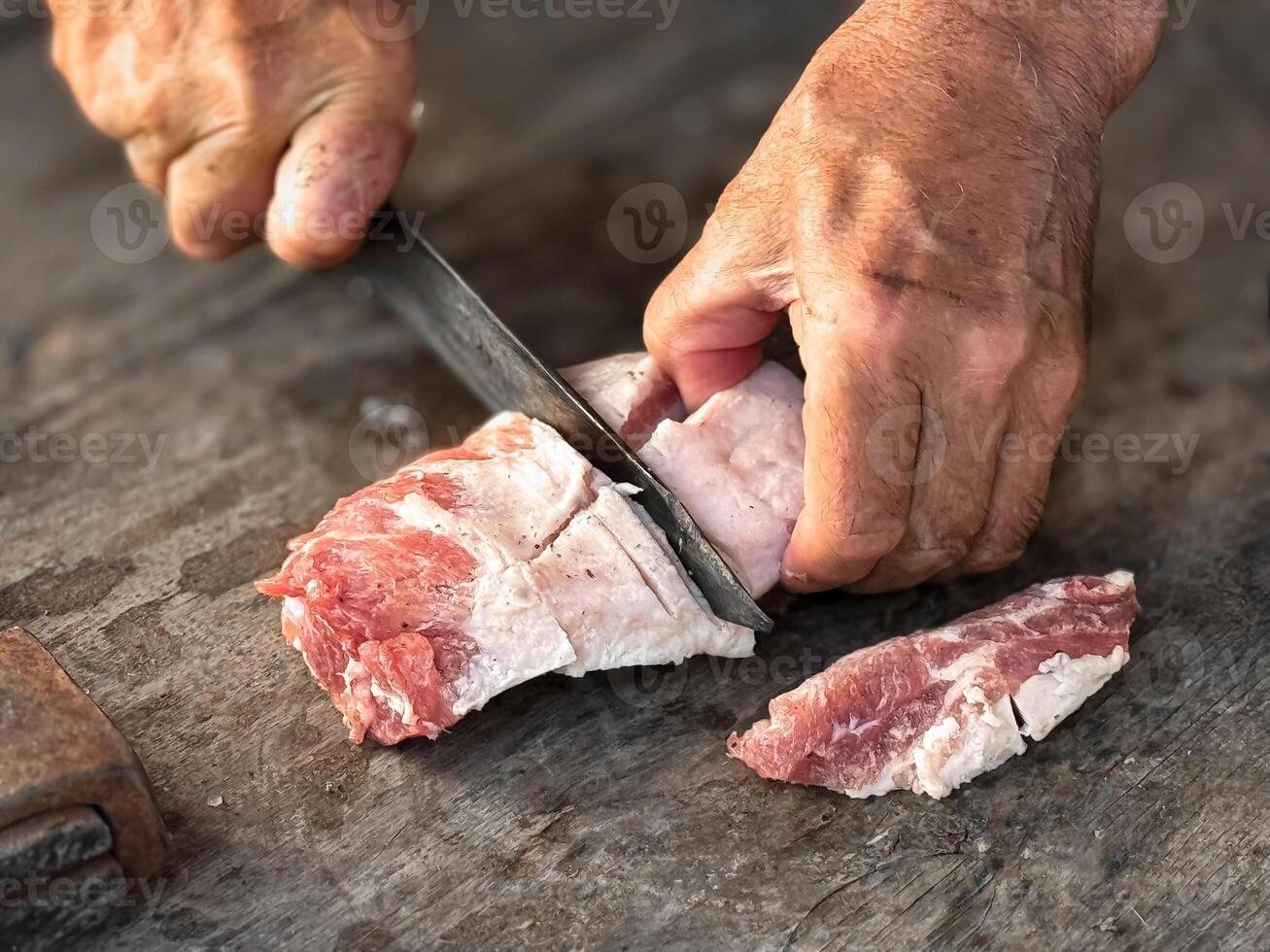 Hands skillfully cutting raw meat on wooden surface for culinary preparation photo