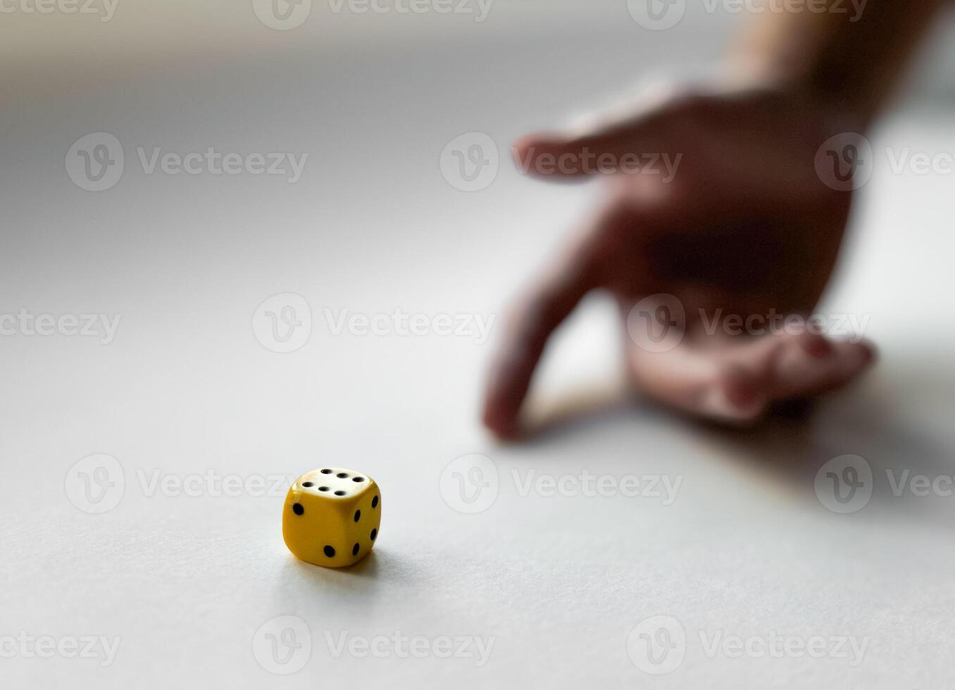 Hand in motion with yellow dice on a white surface capturing chance and luck photo