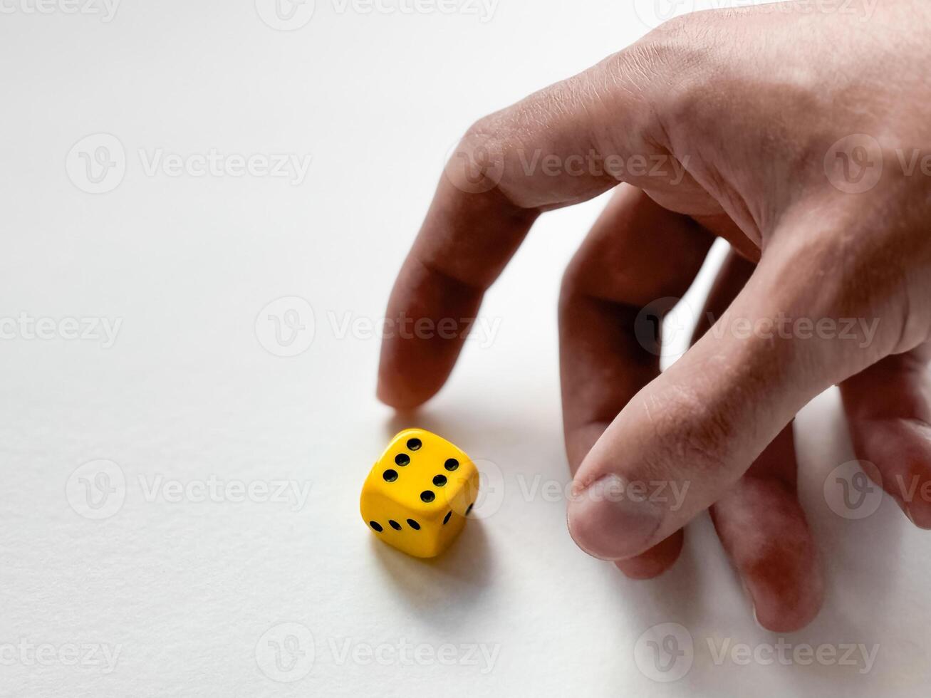 Hand reaching for yellow dice on white background - symbol of chance and decision photo