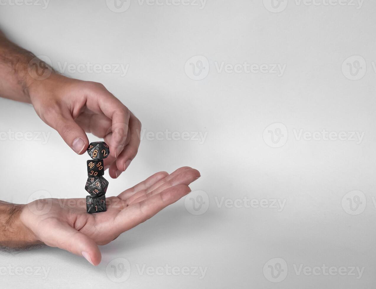 Hands rolling unique polyhedral dice in mid-air against a minimalistic background photo