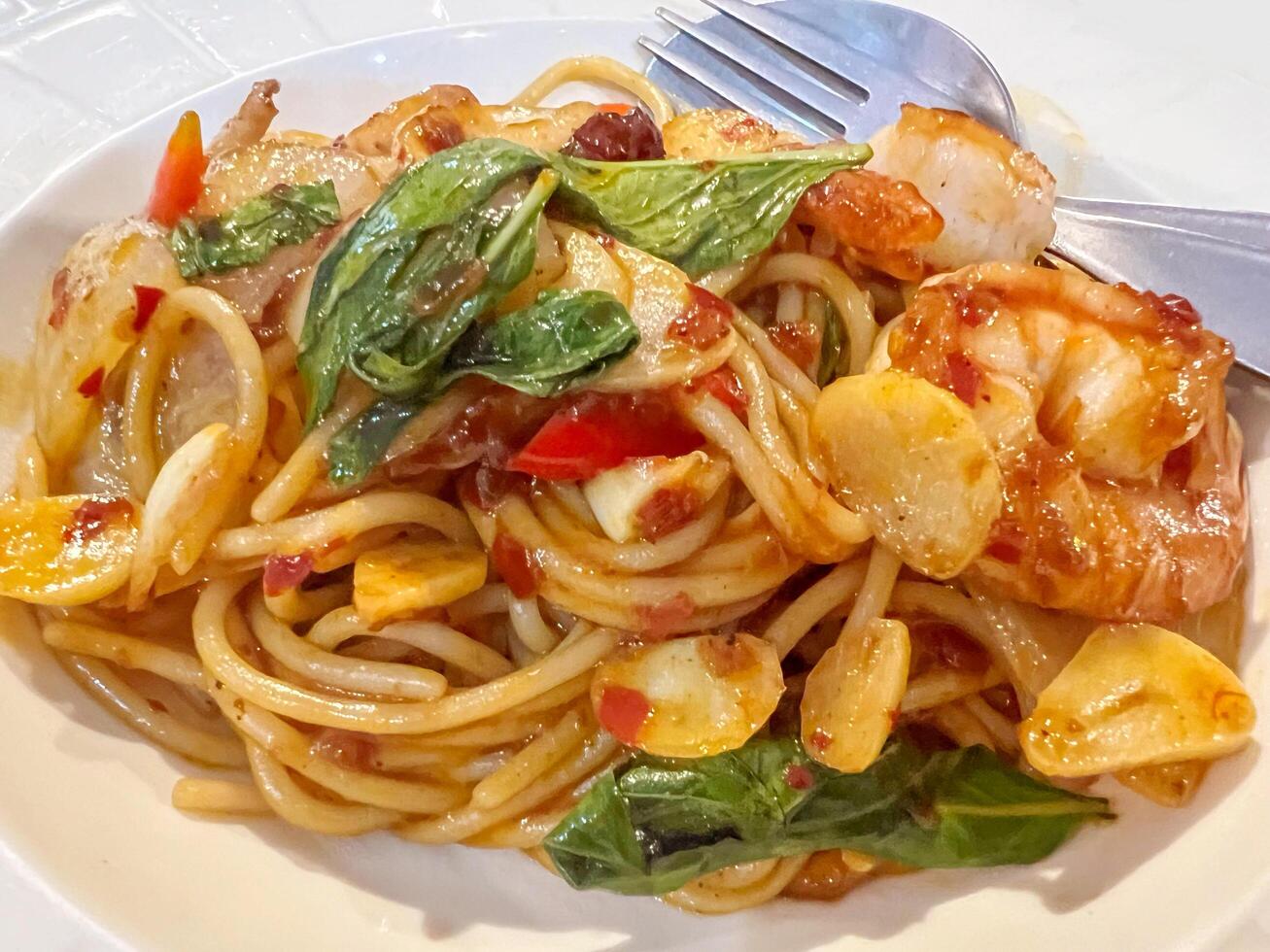 Closeup fusion prawns and squids Stir Fried Chili Paste spaghetti in white ceramic plate. photo
