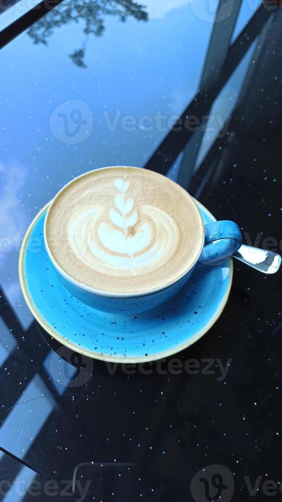 cup of coffee and latte art in blue teacup on the table photo