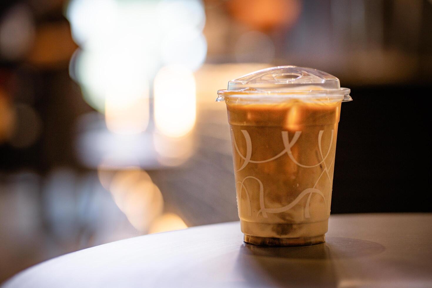 Close up and selective focus glass of ice latte on black table at coffee shop. photo
