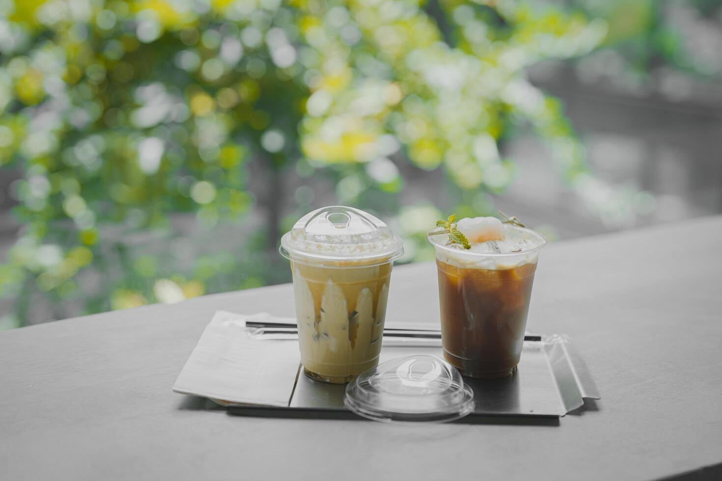 Close up glass of ice black coffee with lychee juice and ice cappucino on raw cement table of a coffee shop summer terrace, menu photography. photo