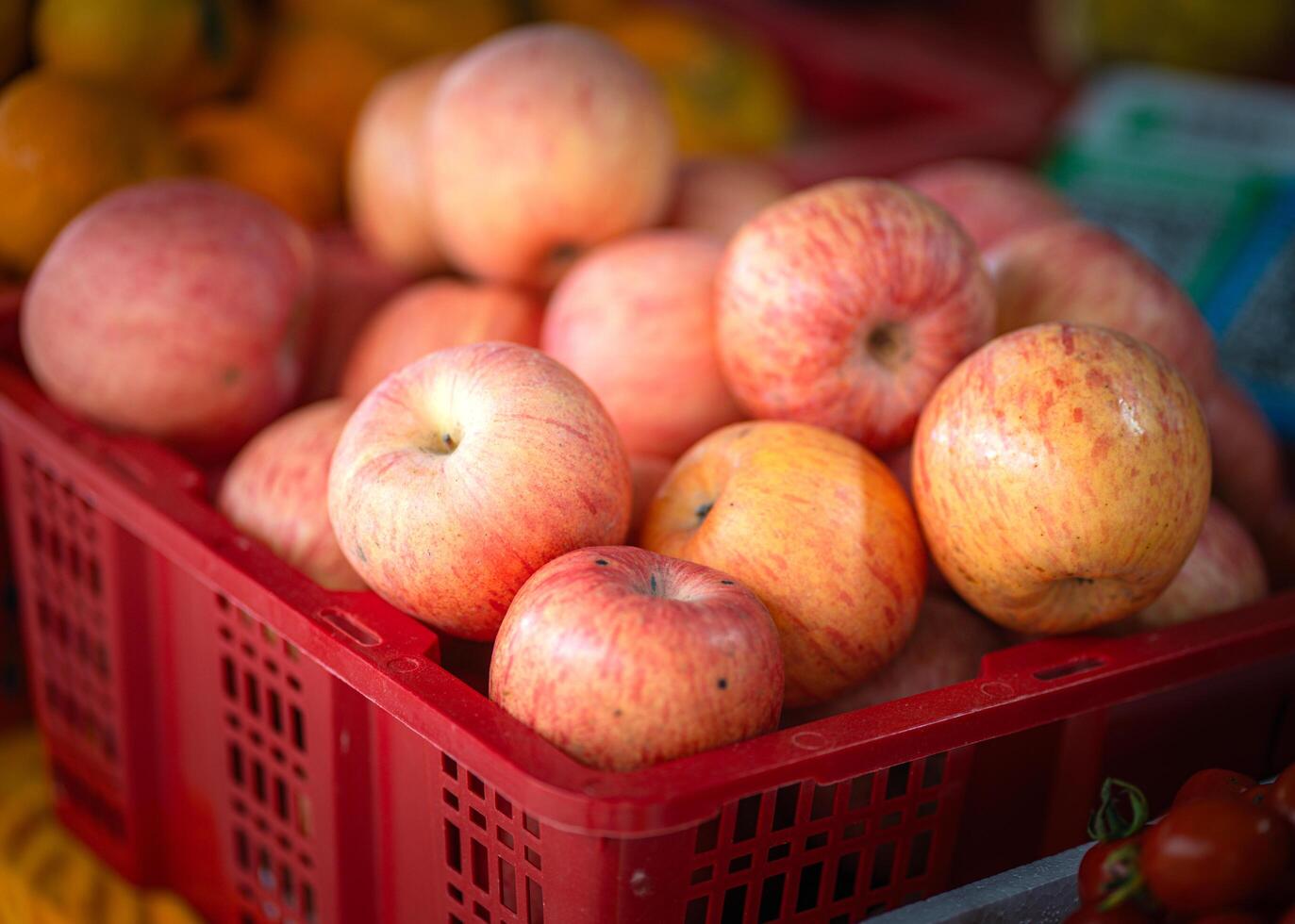 Red basket of fresh apples on a wooden table in a fodd market. photo