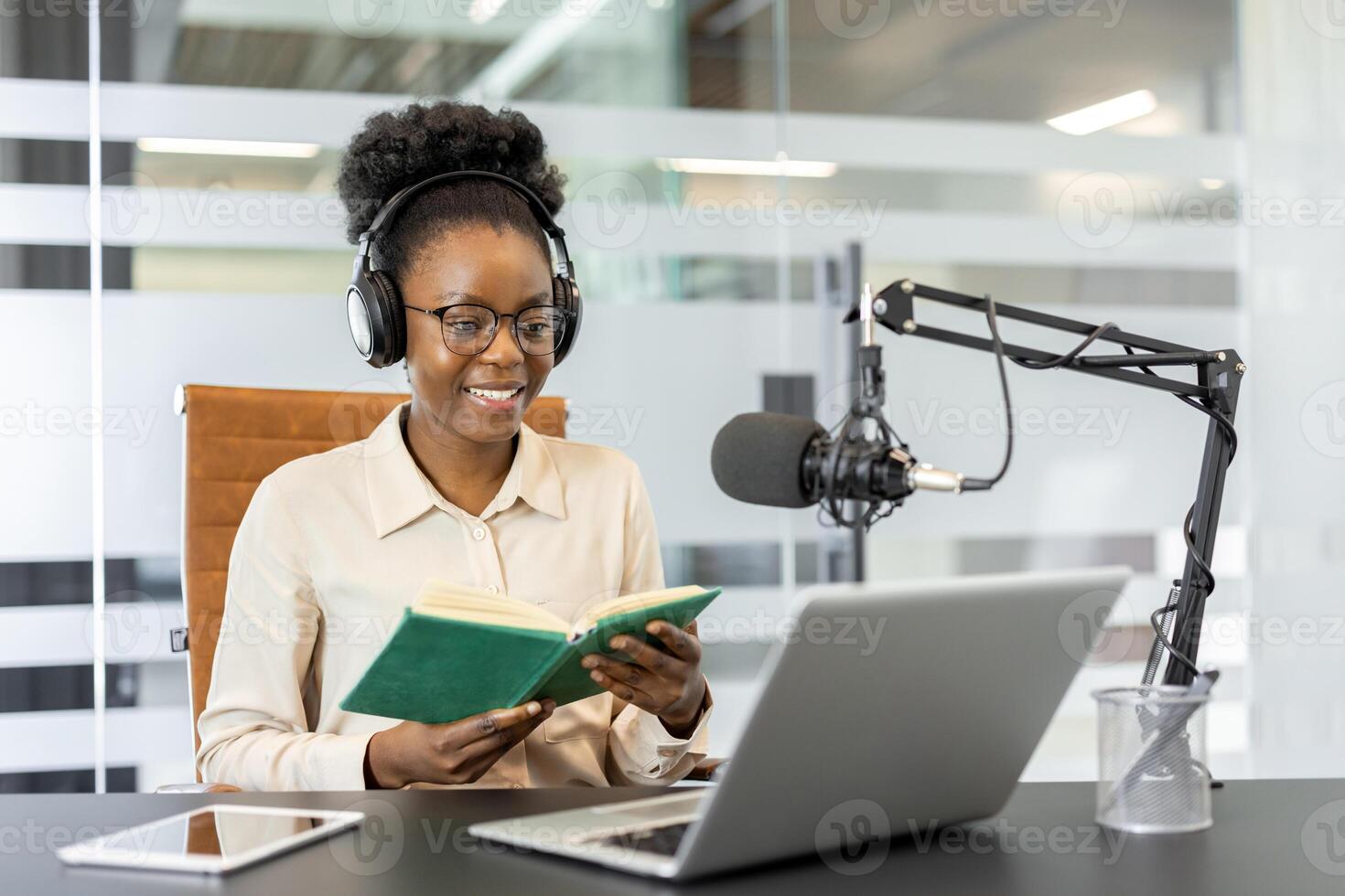 African American businesswoman using laptop and microphone for podcast recording. Concept of technology, broadcasting, and media. Professional and engaging work environment. photo