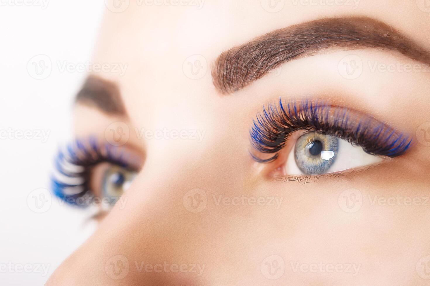 Eyelash Extension Procedure. Woman Eye with Long Blue Eyelashes. Ombre effect. Close up, selective focus. photo