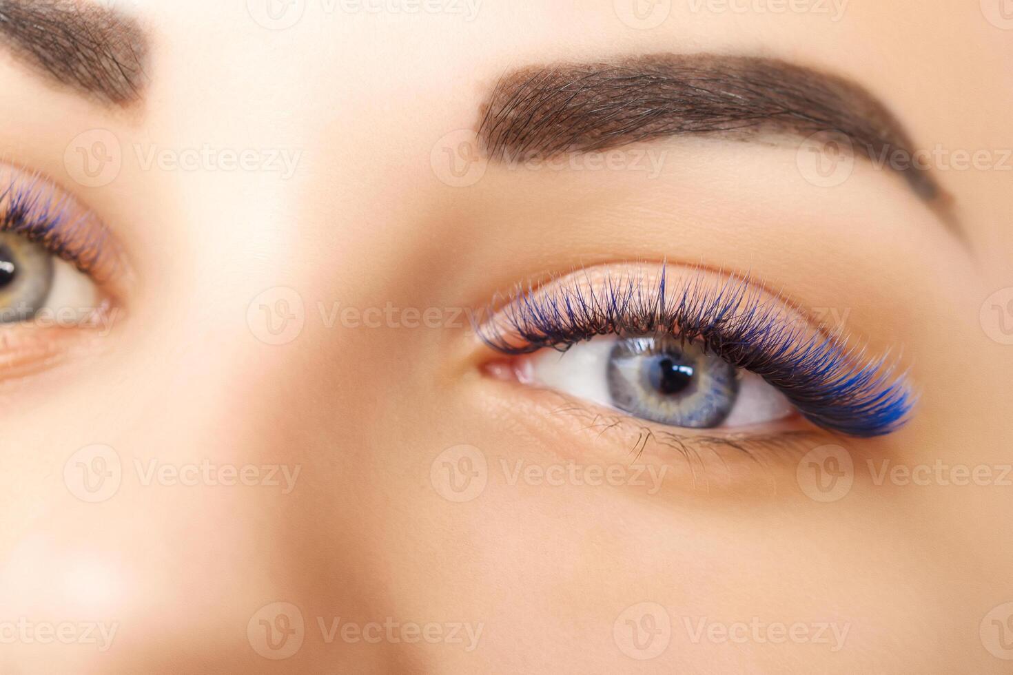 Eyelash Extension Procedure. Woman Eye with Long Blue Eyelashes. Ombre effect. Close up, selective focus. photo