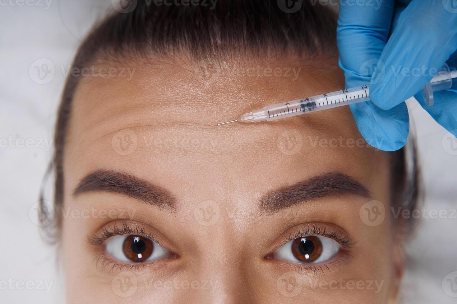 Cropped portrait of young Caucasian woman getting cosmetic injection of botox in forehead. People, cosmetology, plastic surgery and beauty concept. photo