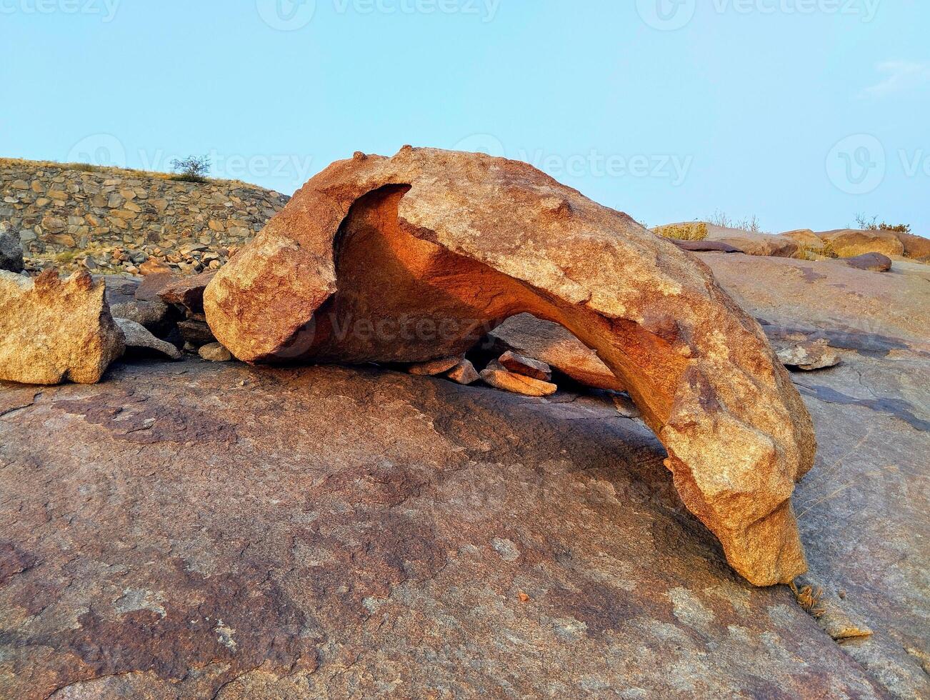 a large rock with a hole in it sitting on top of a hill photo